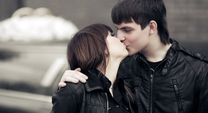Happy young fashion couple kissing on the city street