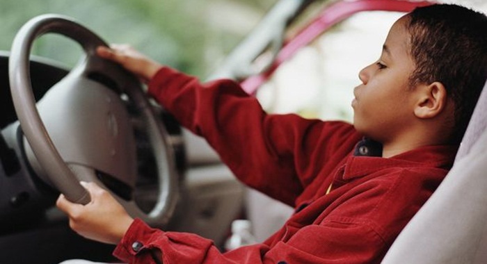Young-child-behind-steering-wheel-of-a-car