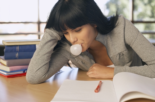 Teenager blowing bubble gum while studying