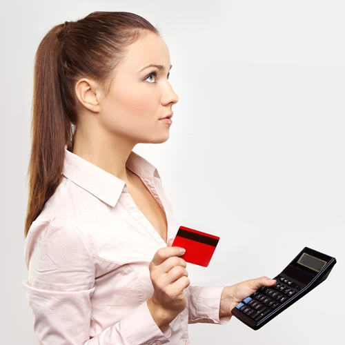 Young woman holding credit card and thinking.