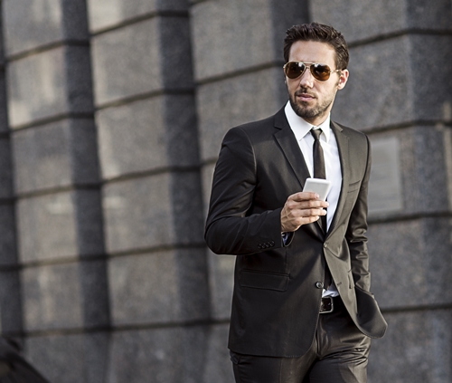 businessman walking in the street while holding a smartphone