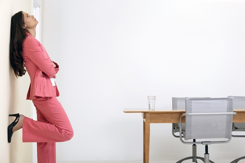 Businesswoman leaning against wall in office