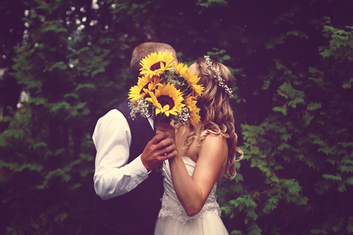 Bride and Groom Kissing Behind Bouquet