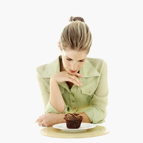 Young woman looking at a muffin on a plate