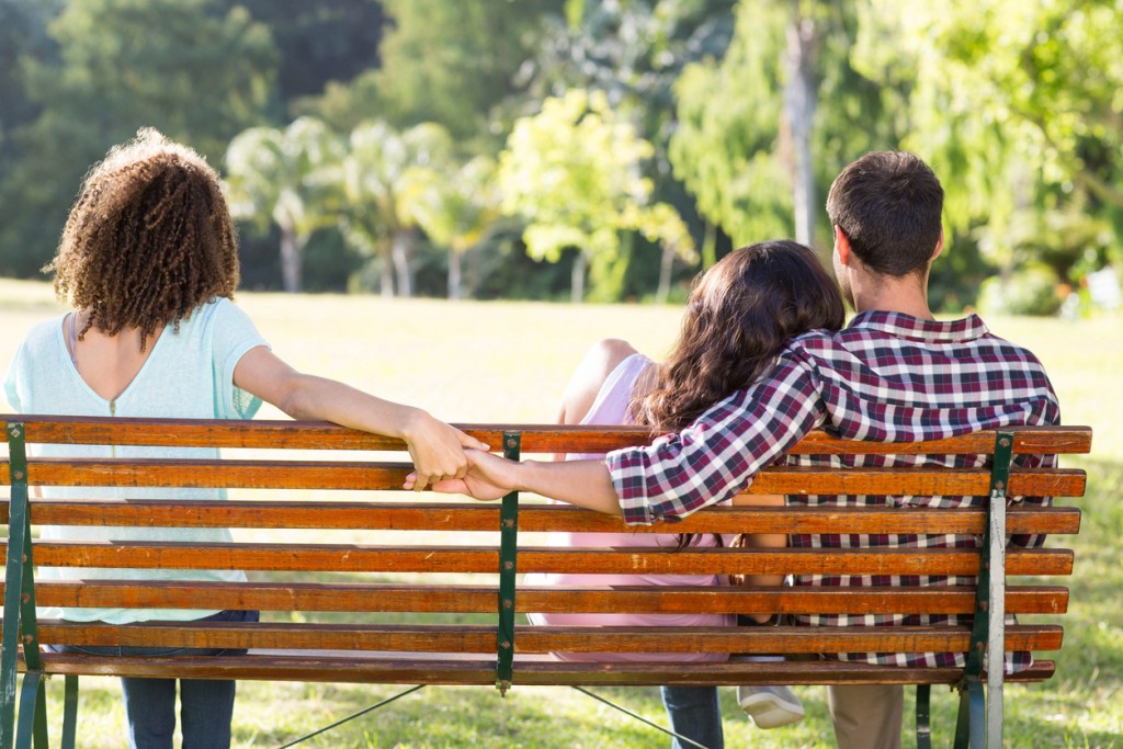 Lonely woman sitting with couple in park