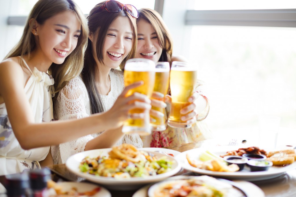Group of girl friends toasting and eating in the restaura
