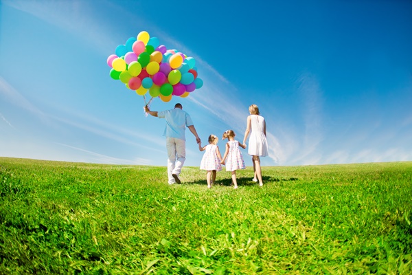 Happy family holding colorful balloons outdoor. Mom, ded and two