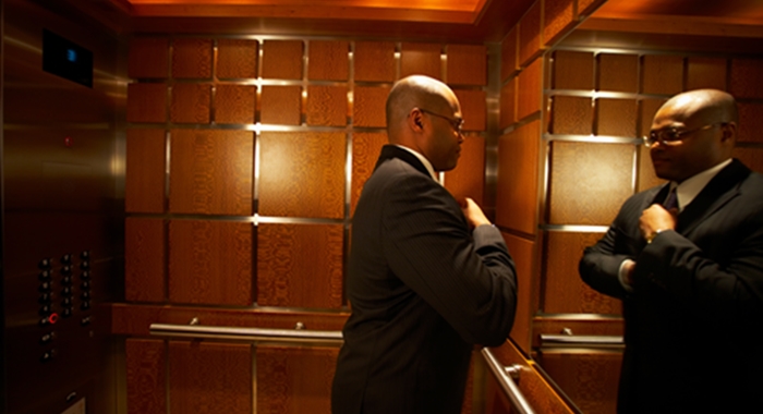 Businessman straightening tie in elevator