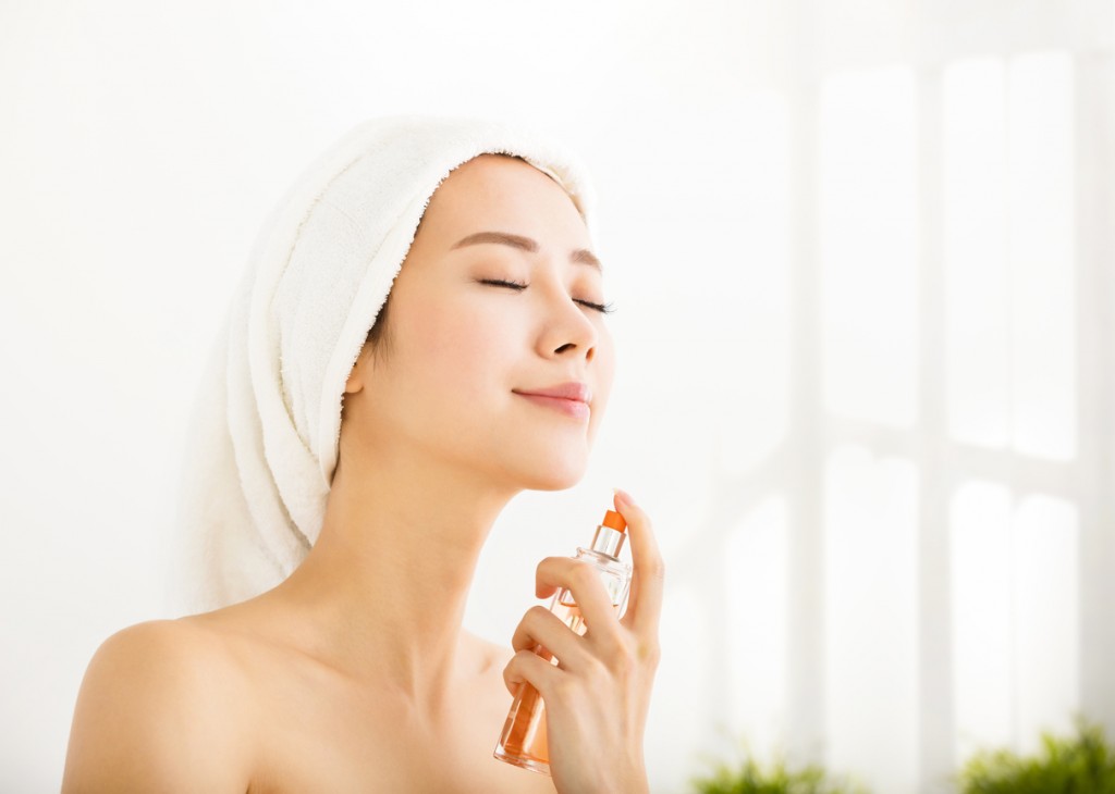 Young beautiful woman applying perfume after bath