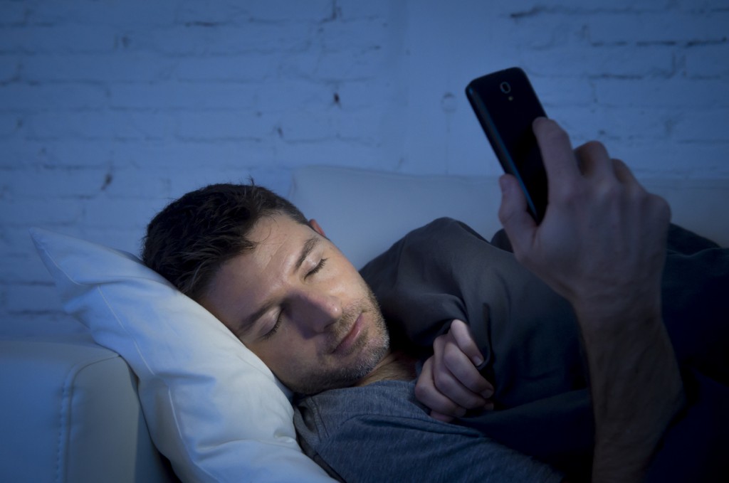 man in couch falling asleep using mobile phone