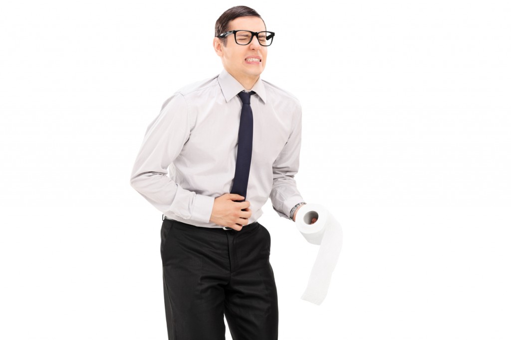 Man with stomach ache holding roll of toilet paper
