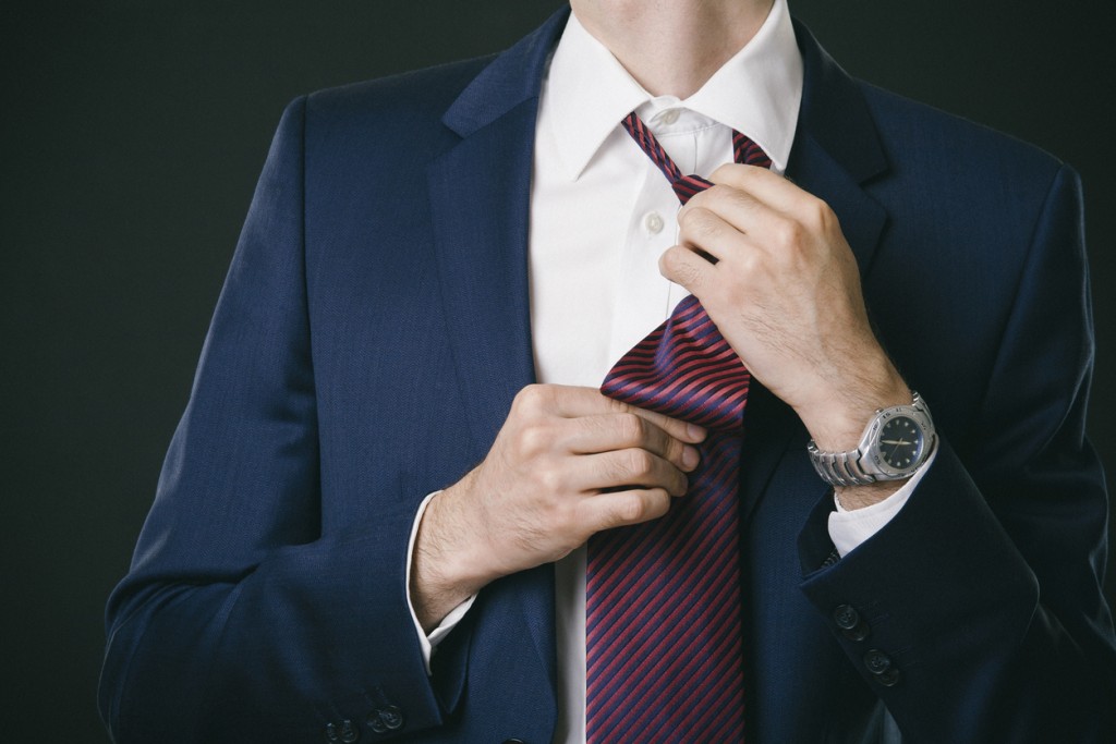 Businessman in the suit tieing the tie