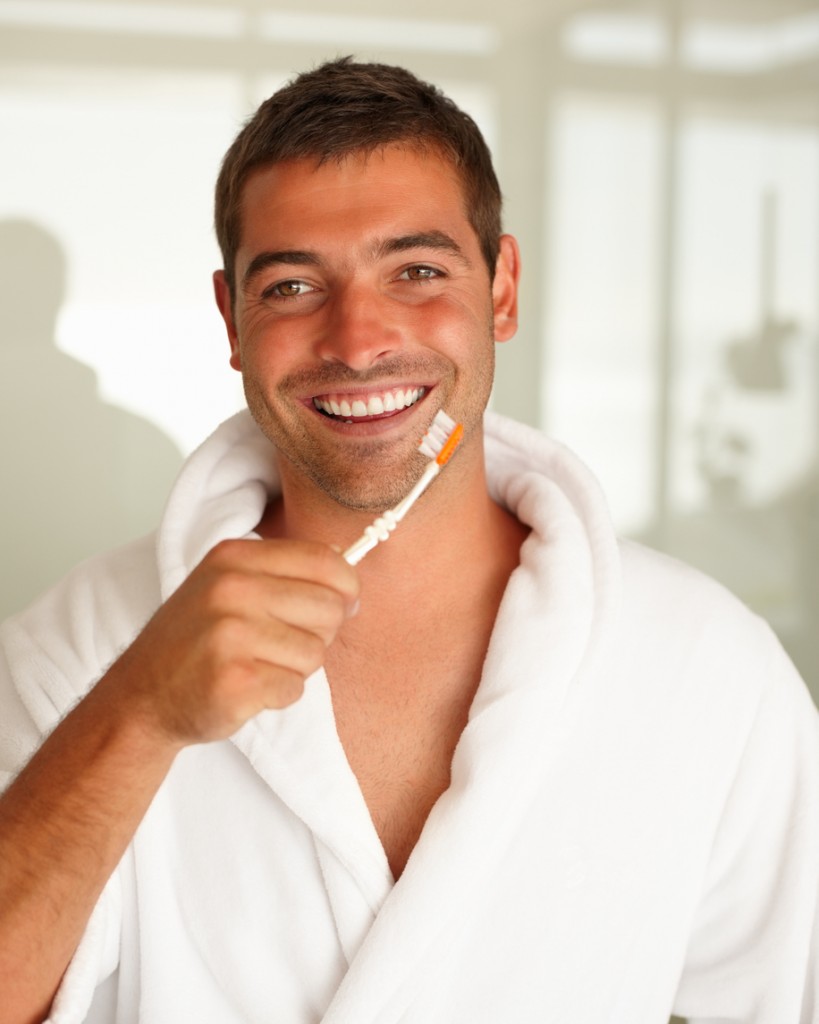 Smiling: Handsome man showing toothbrush