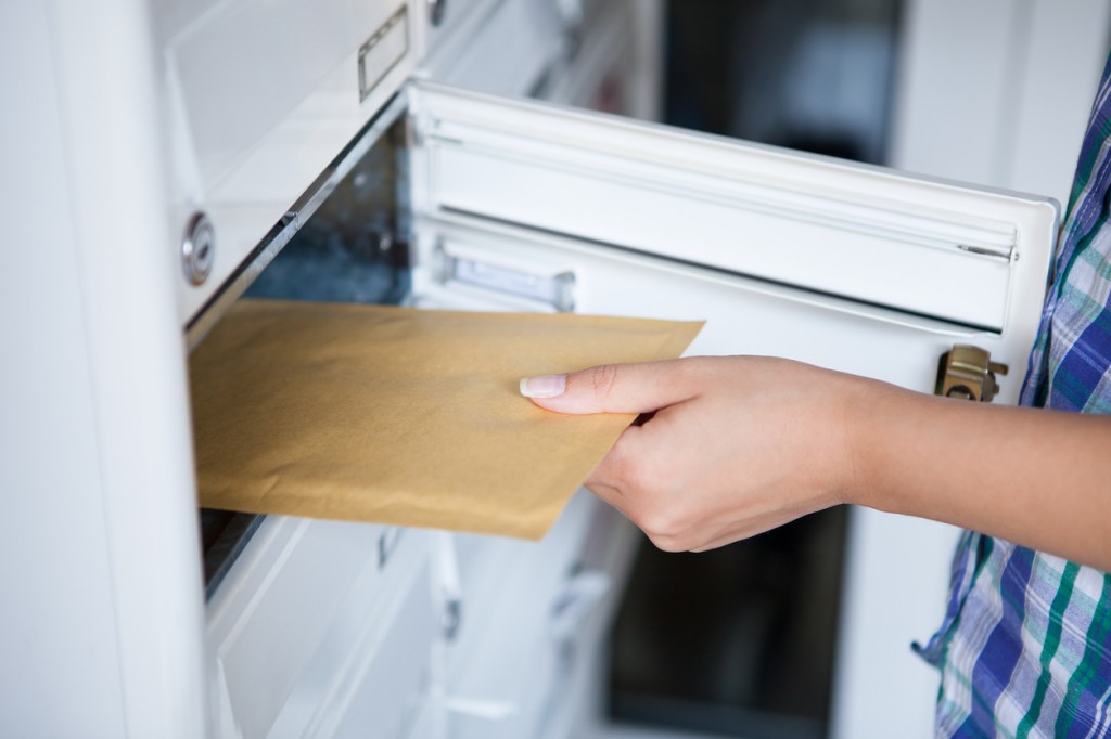 Woman's hand pulling envelop from mailbox