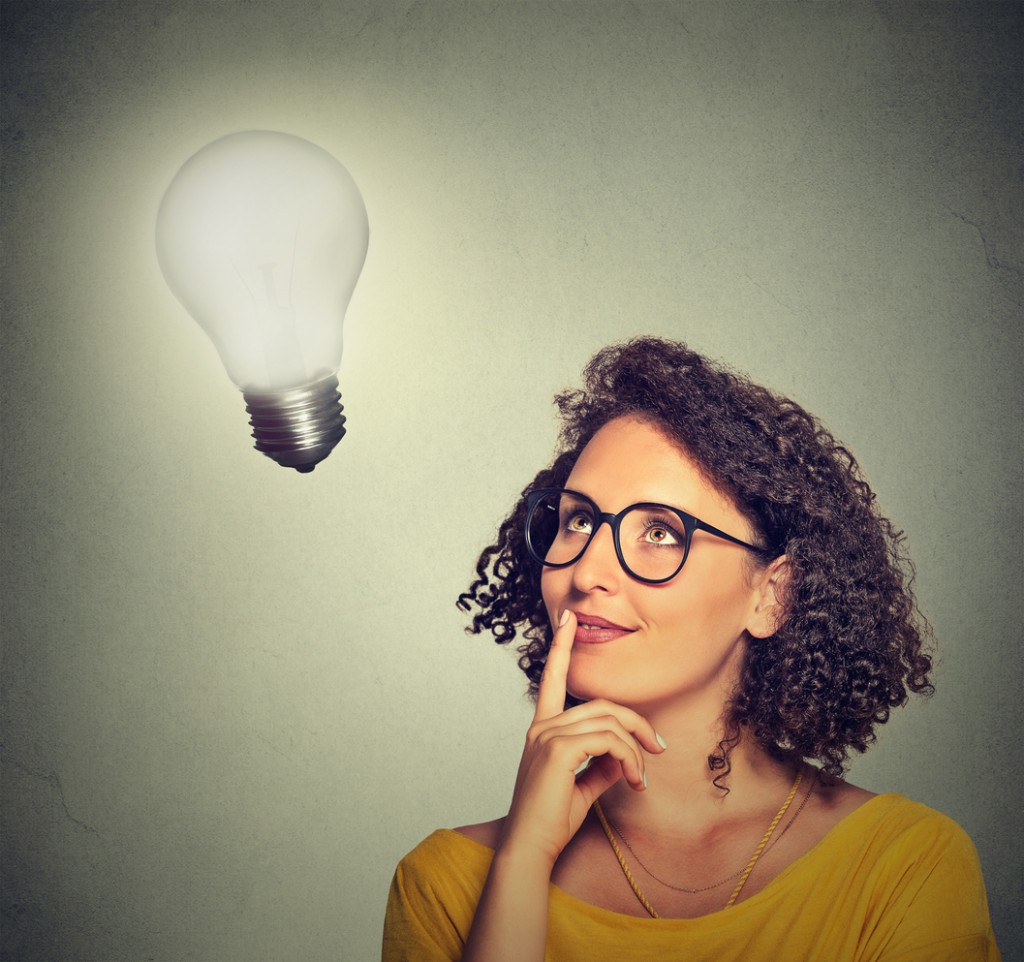 woman thinks looking up at bright light bulb