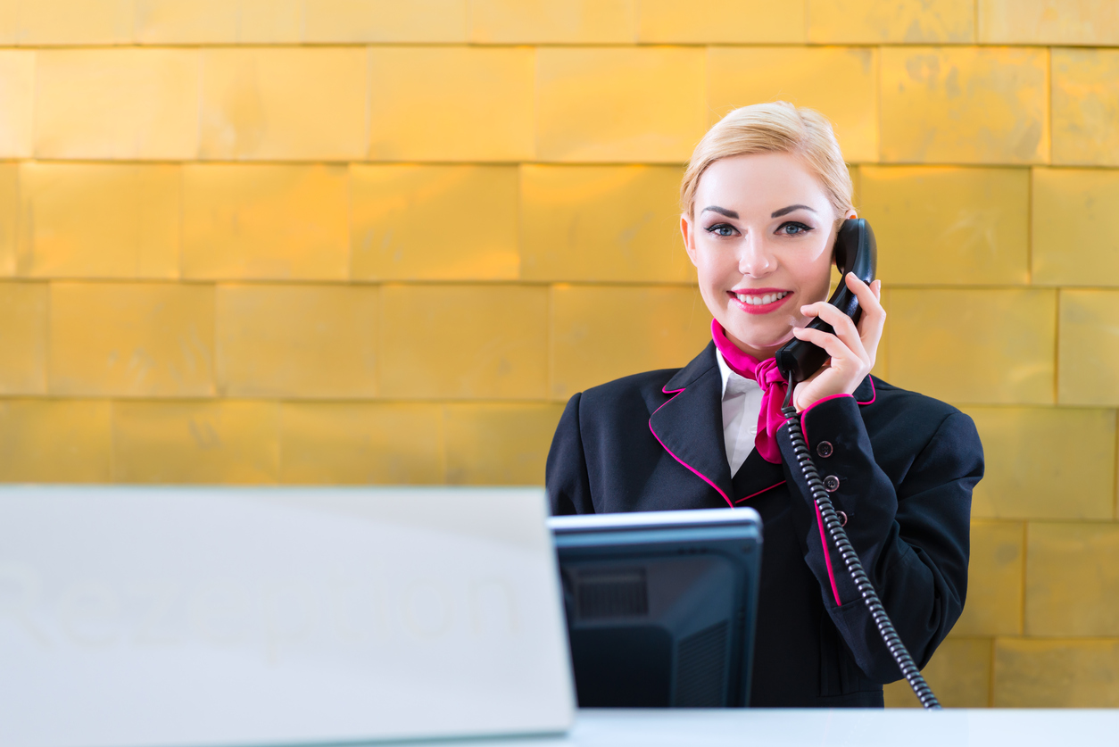 Hotel receptionist with phone on front desk