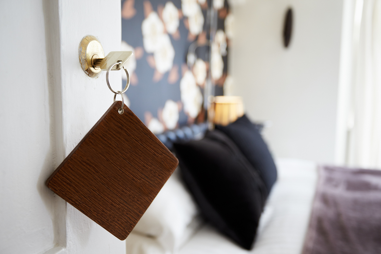 Key And Wooden Fob In Door Of Hotel Bedroom