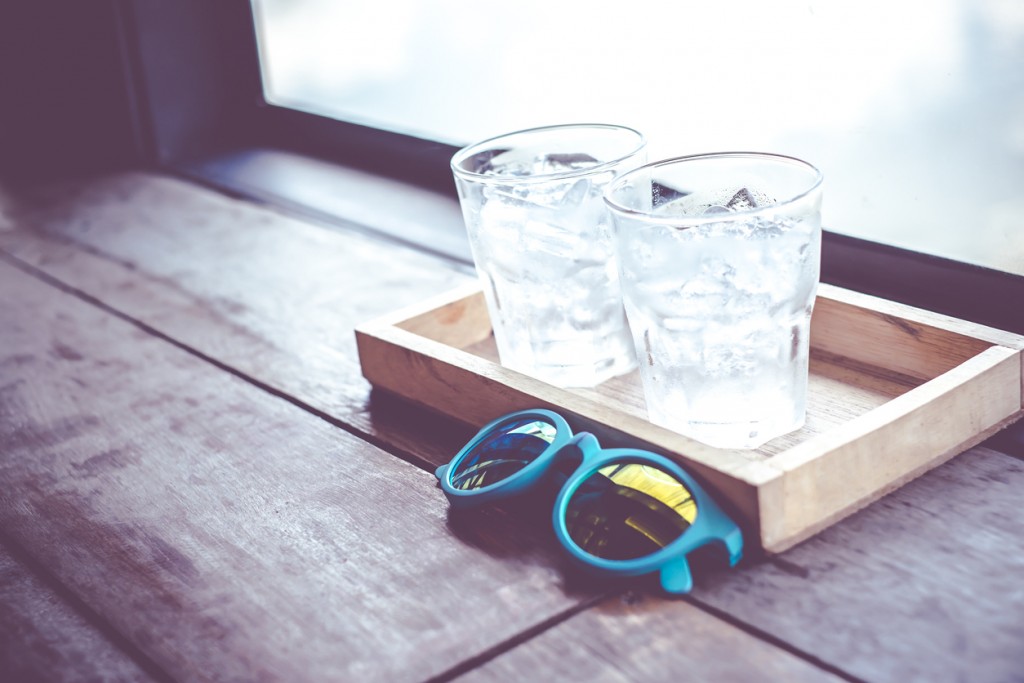 Vintage filter,sunglasses and cold glass of water on wood tray a