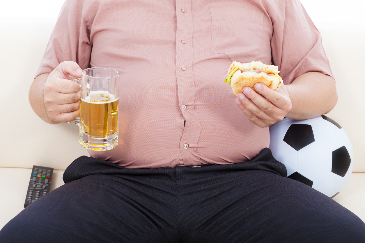 fat business man eating food and beer and sitting on sofa