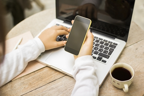 girl with blank cell phone, laptop and cup of coffee