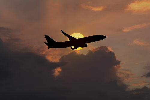 Silhouette of an airplane taking off on sunset background