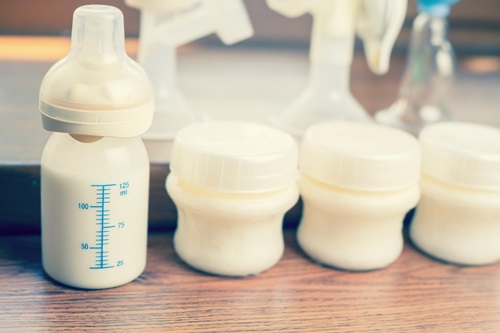 Manual breast pump and milk at background