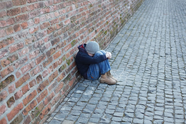 homeless boy leaned against the wall