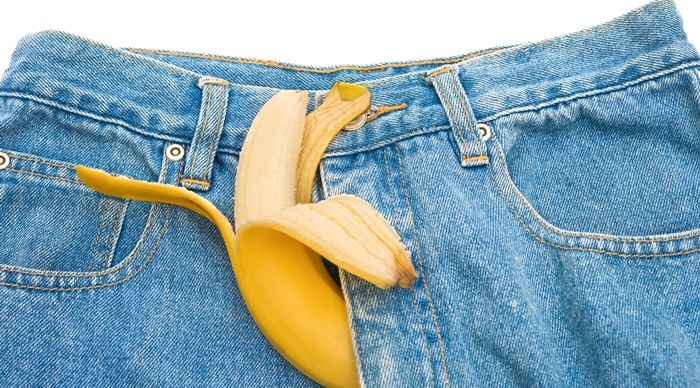 big banana sticks out of mens jeans as potency concept