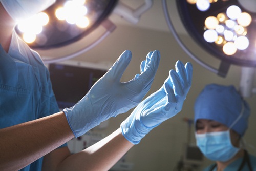 Midsection view of hands in surgical gloves and lights