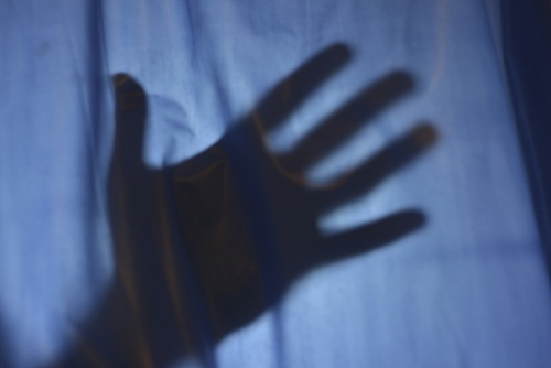 A shadow of a hand on a dark shower curtain