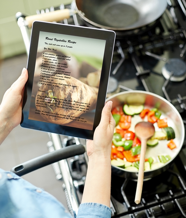 Woman reading recipe on digital tablet in kitchen