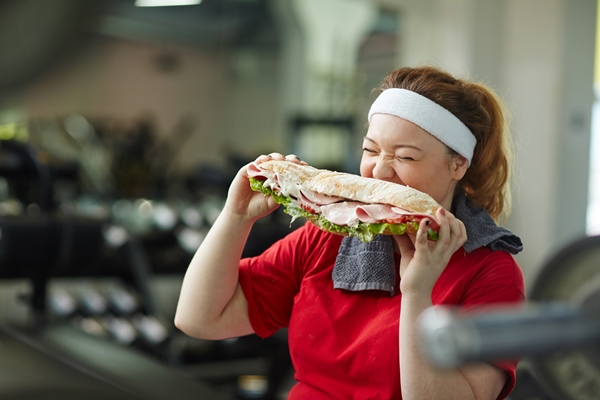 Obese Woman Biting Into Huge Snack in Gym