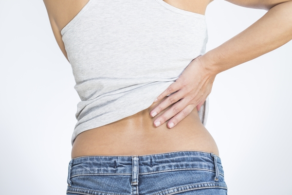 A woman holding her lower back signifying back pain