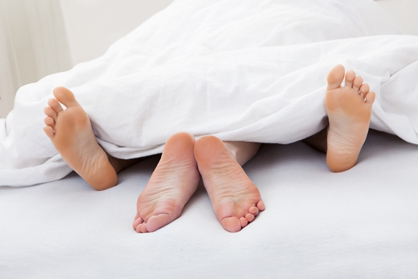 Close-up of couple's feet sleeping on bed