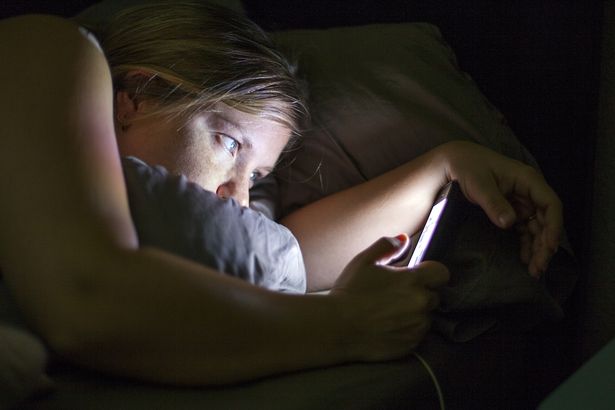 Caucasian-woman-using-cell-phone-in-bed