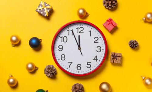 Alarm clock and gifts with baubles on yellow background.