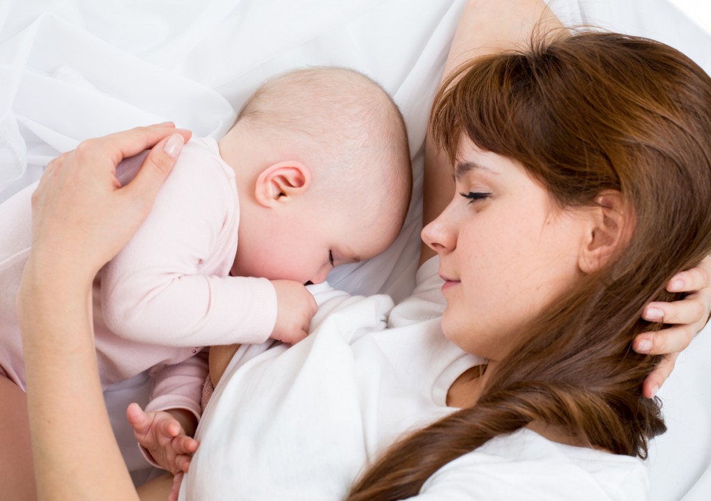 A mother breast-feeding her baby in bed