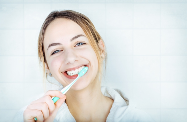 Happy young woman brushing teeth .