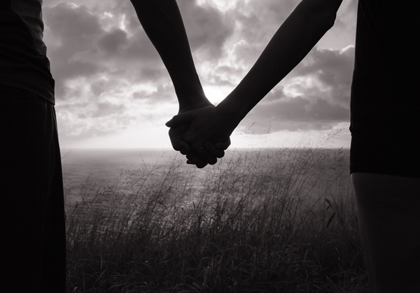 Black and white image of couple holding hands in silhouette